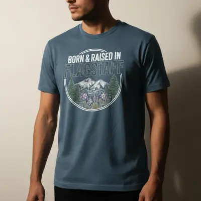 Man wearing denim blue Comfort Colors t-shirt featuring Born and Raised in Flagstaff 928 AZ city pride graphic on front chest