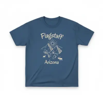Denim blue Comfort Colors garment-dyed t-shirt featuring a minimalist Flagstaff Arizona skyline illustration with the San Francisco Peaks and Route 66 corridor