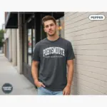 portsmouth-varsity-shirt-nh-hometown-pride-tee-comfort-colors-t-shirt-urban-street-male-young-pepper.webp Young man wearing a pepper black Comfort Colors t-shirt featuring a Portsmouth NH varsity-style hometown pride graphic on the front chest
