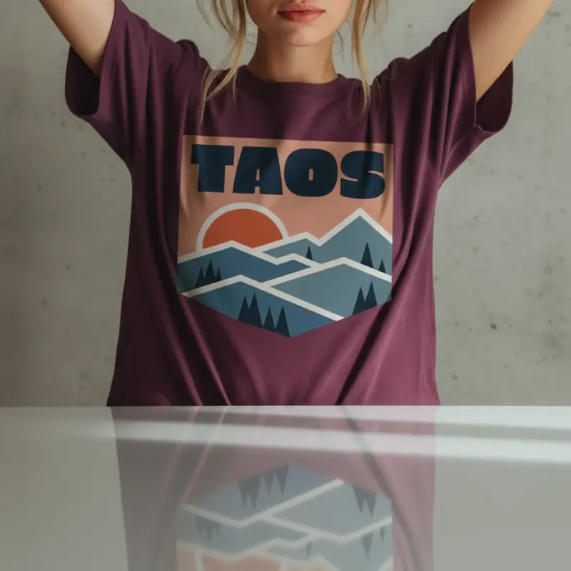 taos-skyline-shirt-adobe-mountain-new-mexico-tee-comfort-colors-t-shirt-creative-female-berry.webp Woman wearing a berry Comfort Colors t-shirt featuring a minimalist Taos New Mexico skyline illustration with adobe architecture and Wheeler Peak