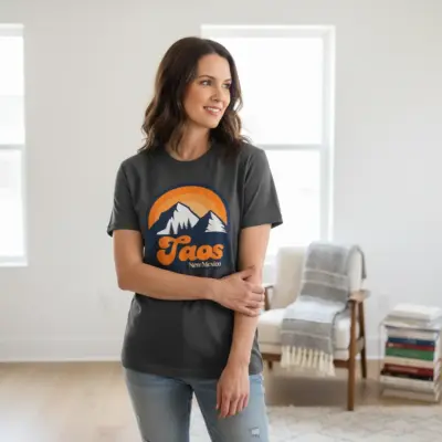 Woman wearing a pepper-colored vintage Taos New Mexico retro hometown tee indoors, front chest graphic with distressed southwestern typography